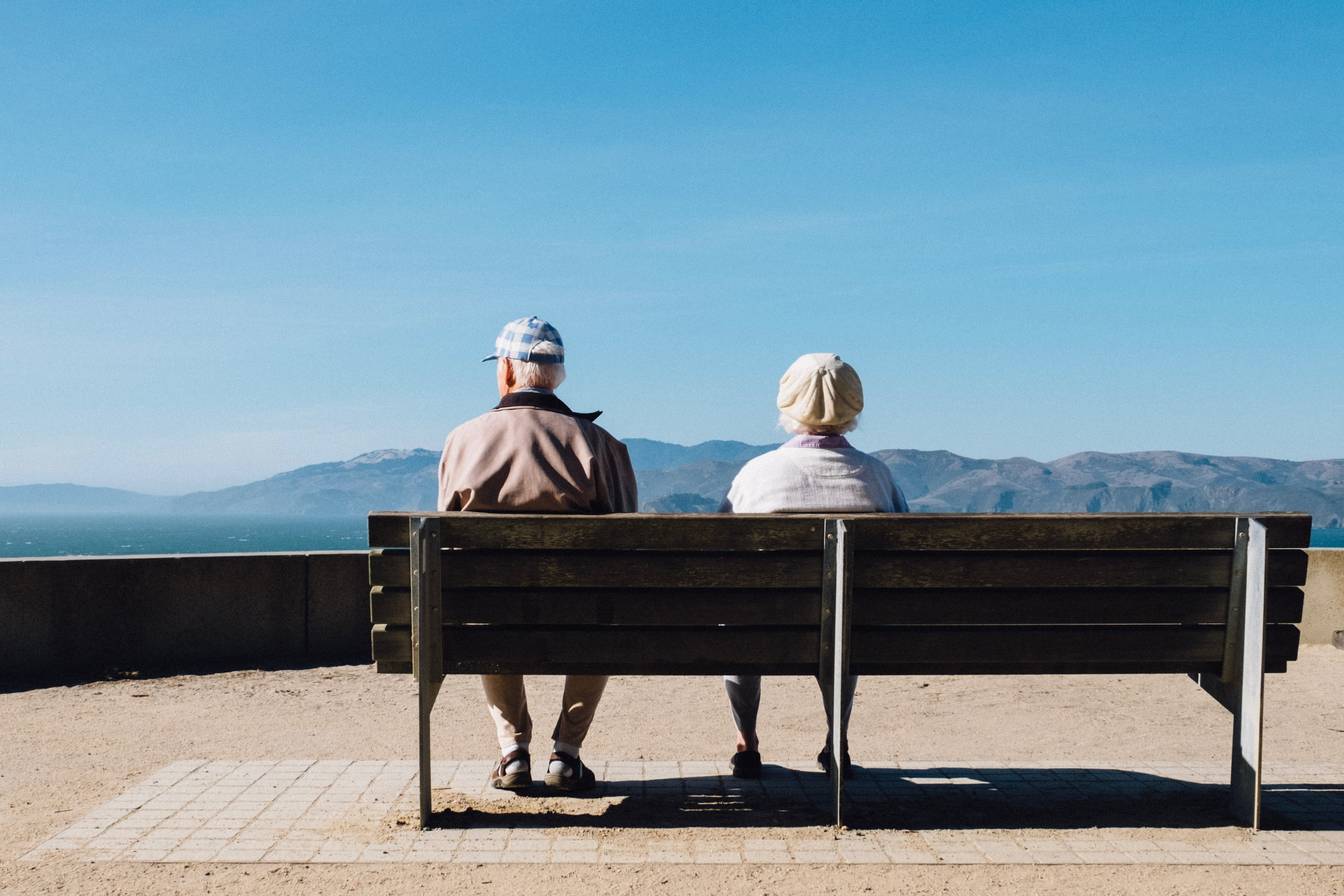 older couple sitting on a bench looking at the landscape 