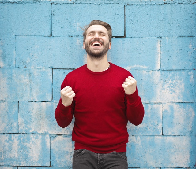 Hppy man standing in front of a wall