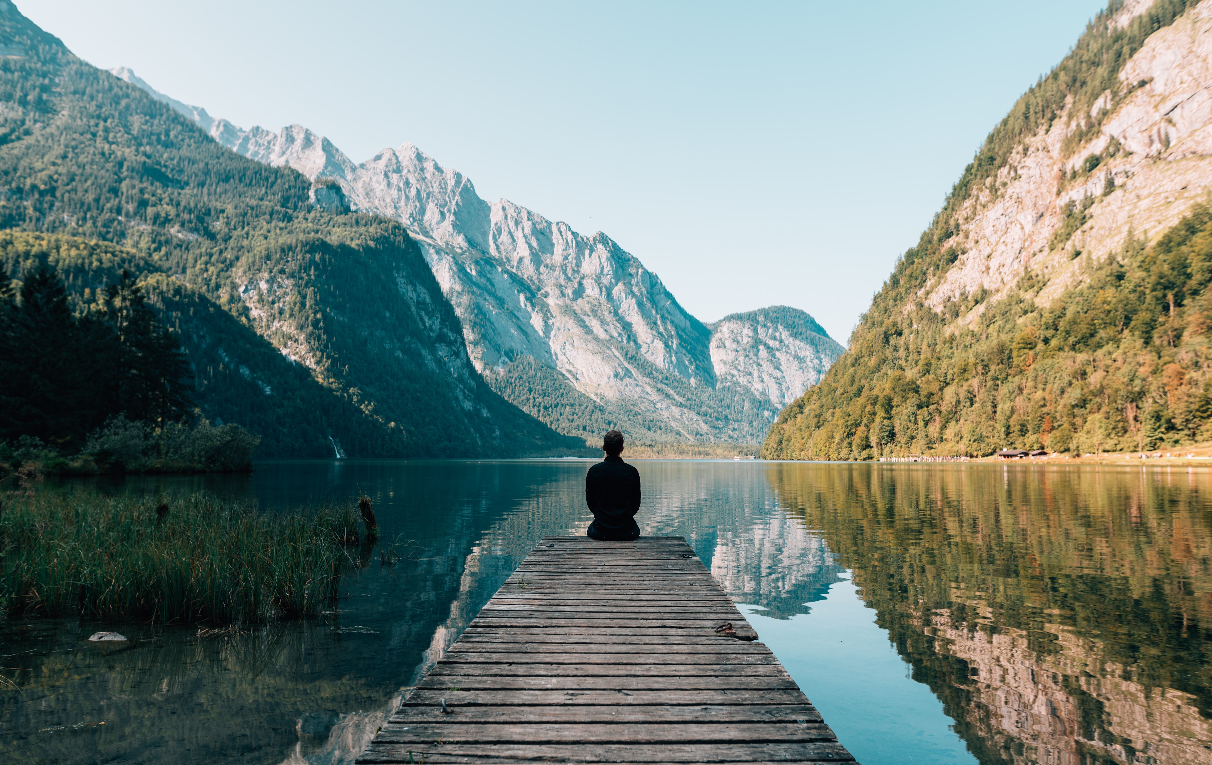 Person sitting on end of dock looking at mountains