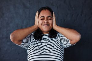 Woman covering ears with hands.