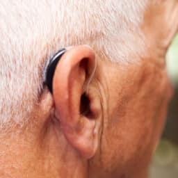 Close up of an older man wearing a behind-the-ear hearing aid.