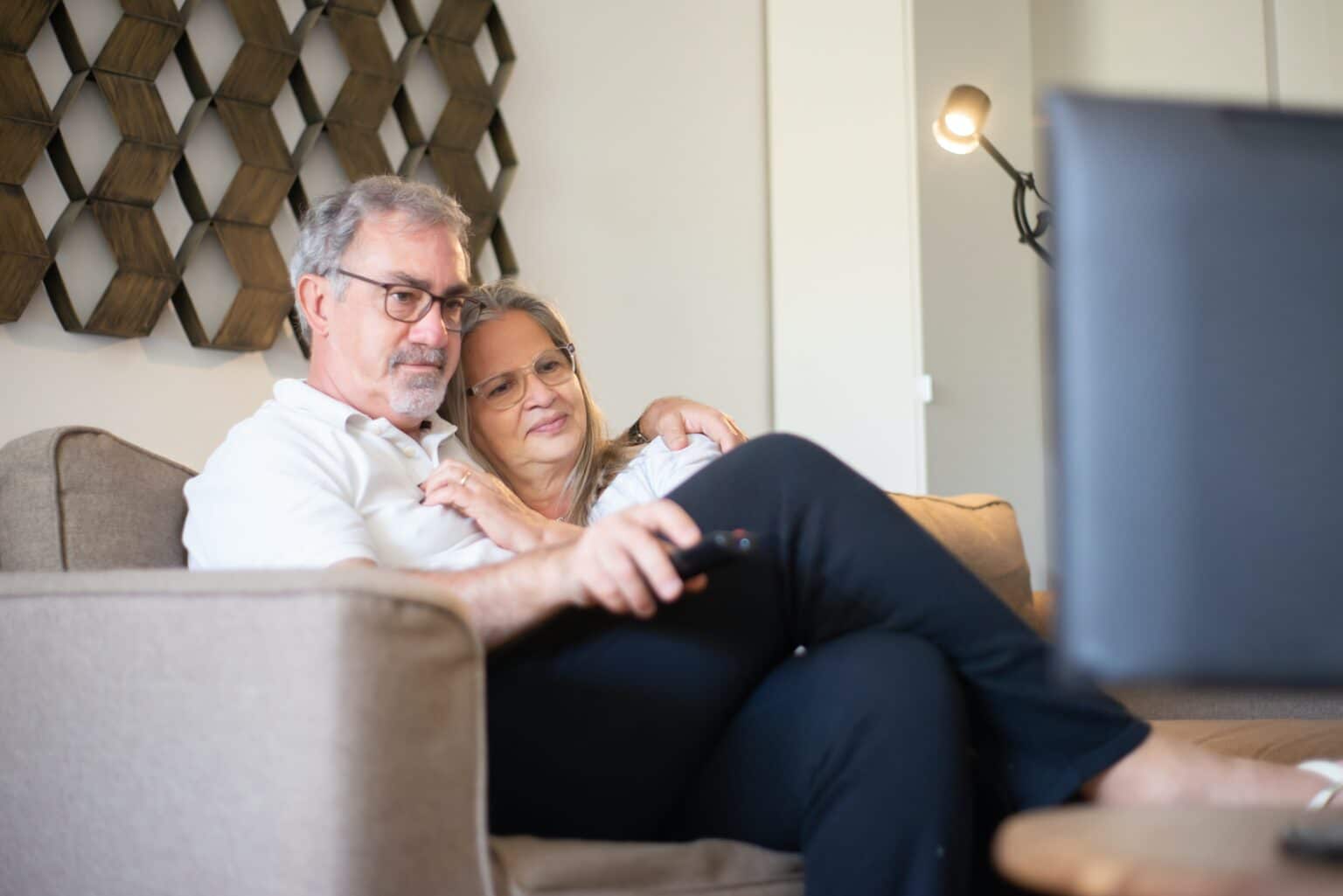 Older couple watching television together at home.