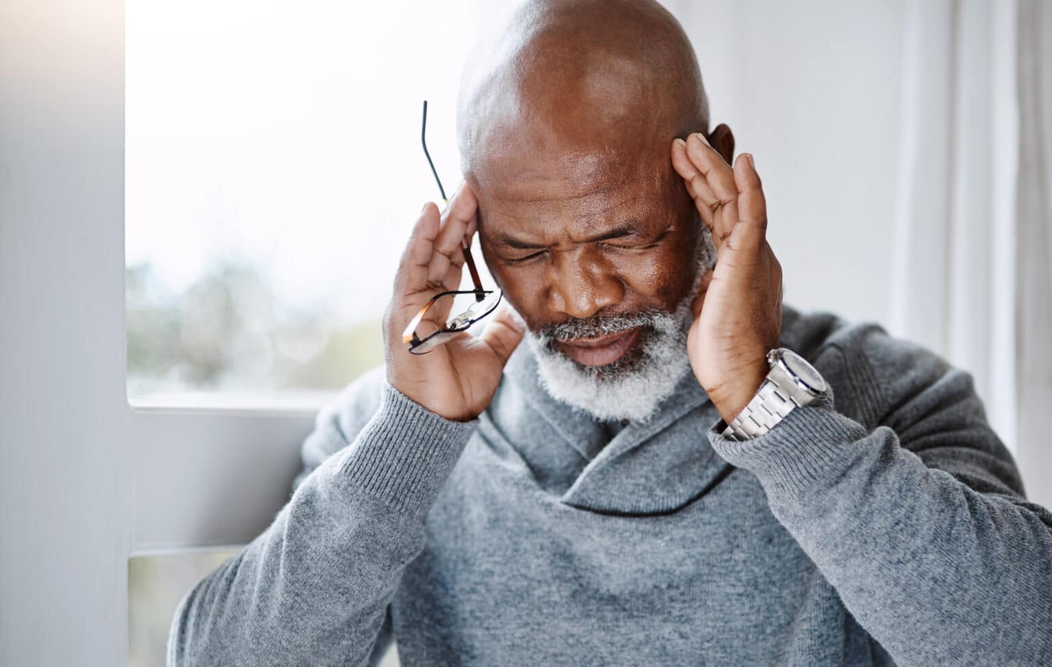 Senior man with a headache rubbing his temples.