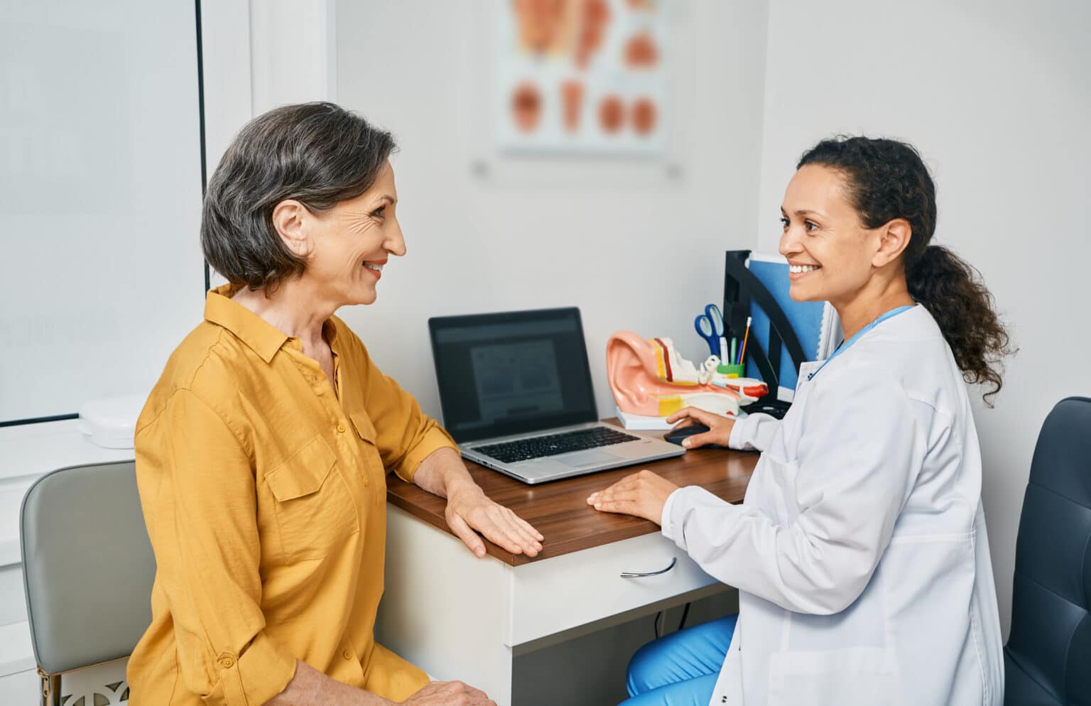 Senior woman talking to an audiologist about hearing loss treatment options.