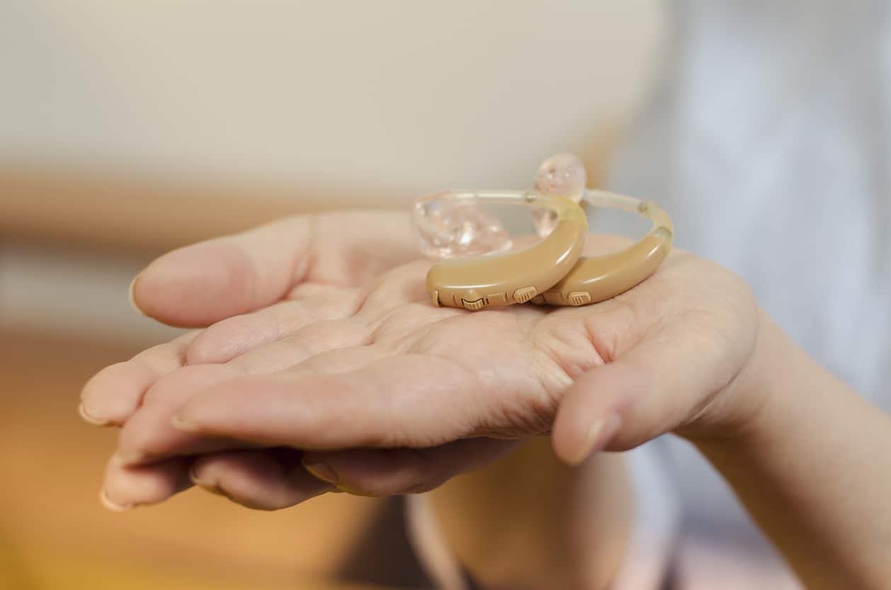 Woman showing hearing aids in her hands.