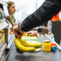 Person putting bananas on the grocery conveyor belt