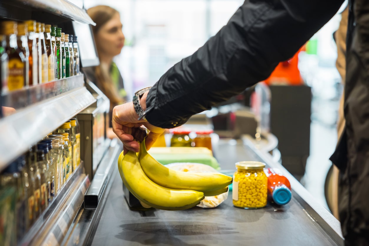 Person putting bananas on the grocery conveyor belt.