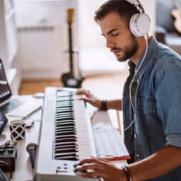 Young musician wearing headphones playing the keyboard