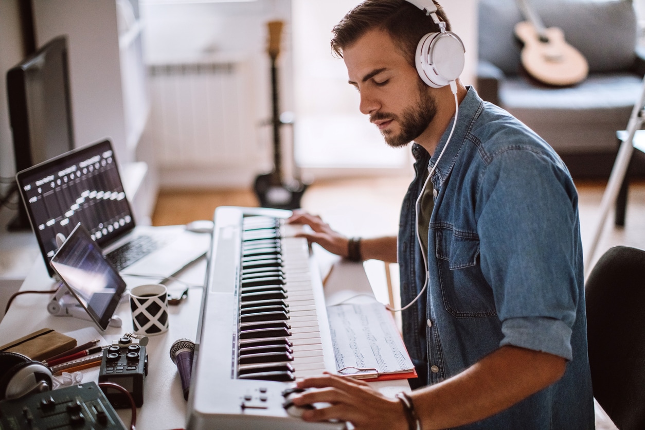 Young musician wearing headphones playing the keyboard.