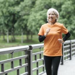 Athletic Senior woman running outdoor jogging in park.