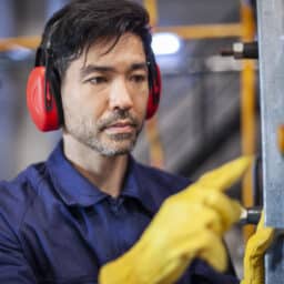 Man with earmuffs working on a machine