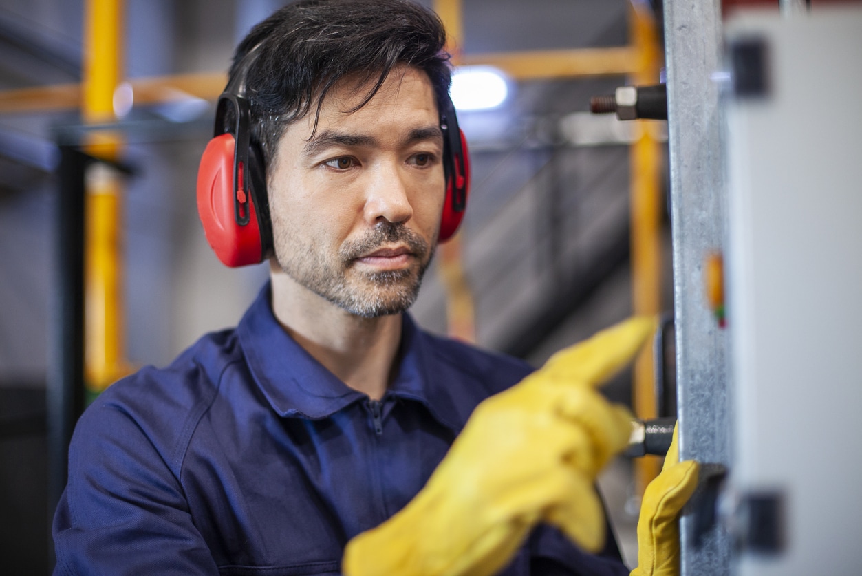Man with earmuffs working on a machine.