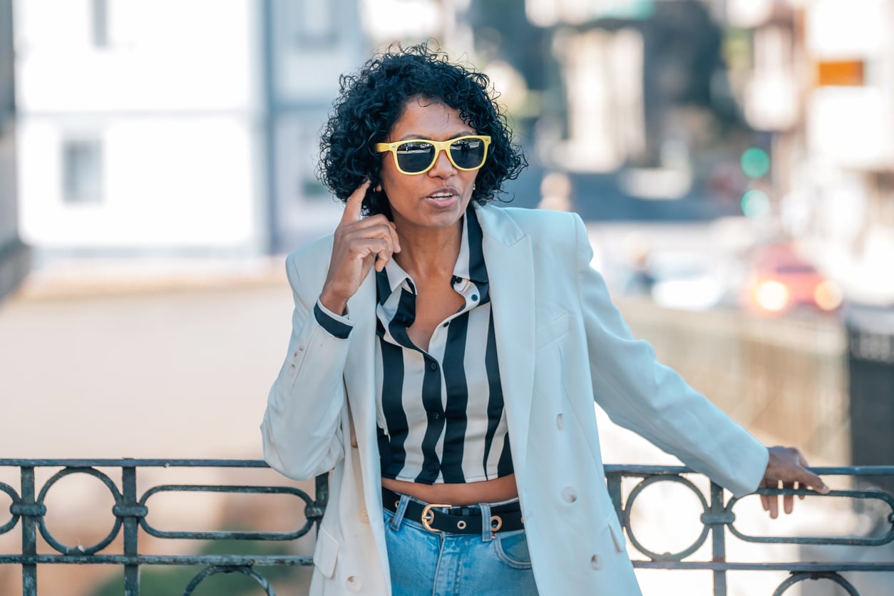Woman touches ear with sunglasses