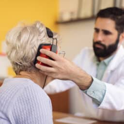An audiologist fits their patient with headphones for a hearing test.