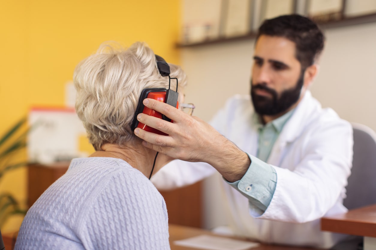 An audiologist fits their patient with headphones for a hearing test.